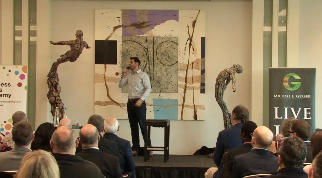 Ian Edwards on stage between two of his bronze figurative sculptures