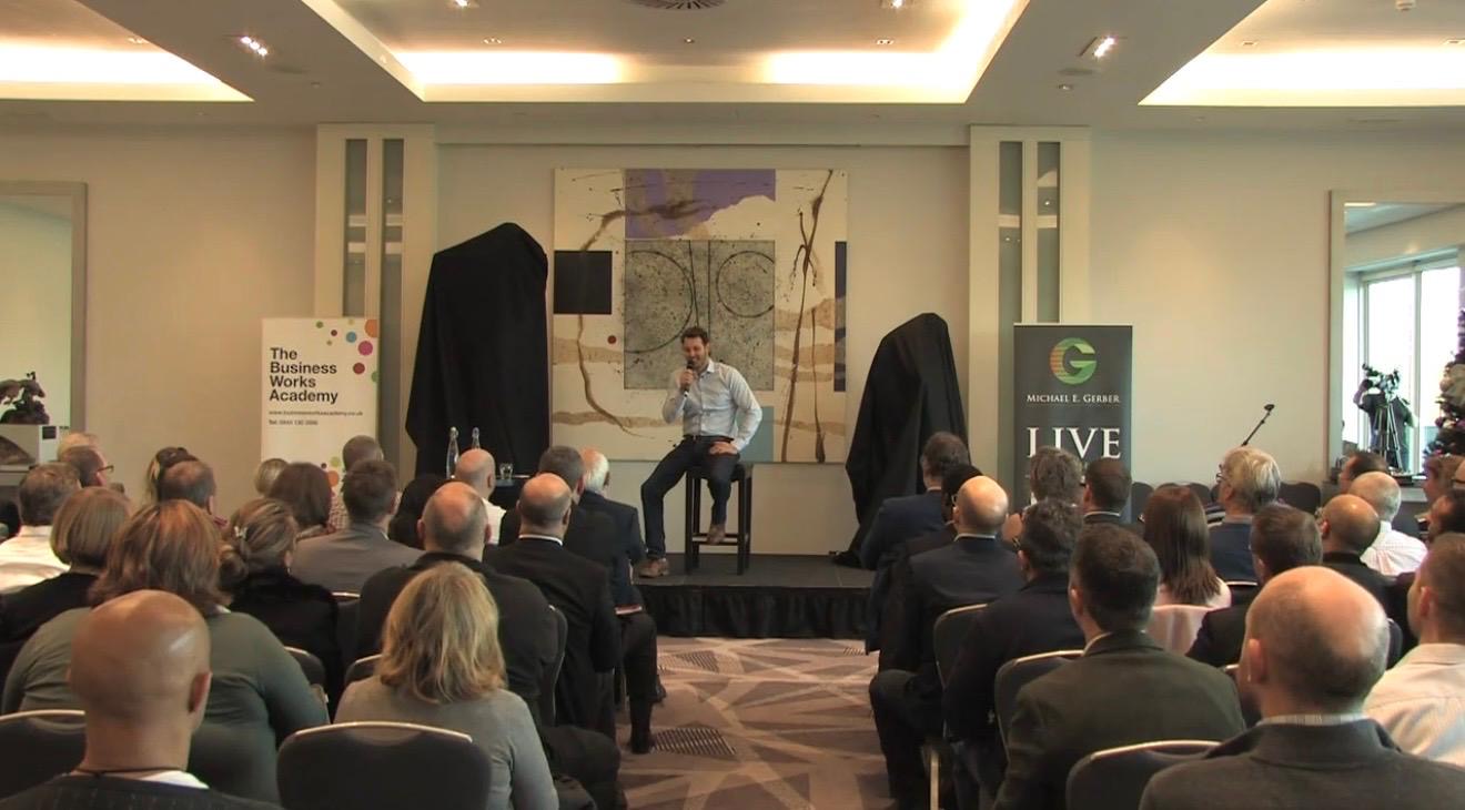 Ian Edwards speaking on stage to a seated conference audience