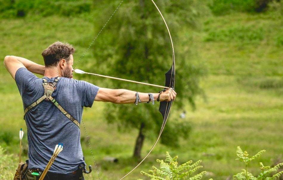Ian Edwards drawing a traditional longbow in an open field